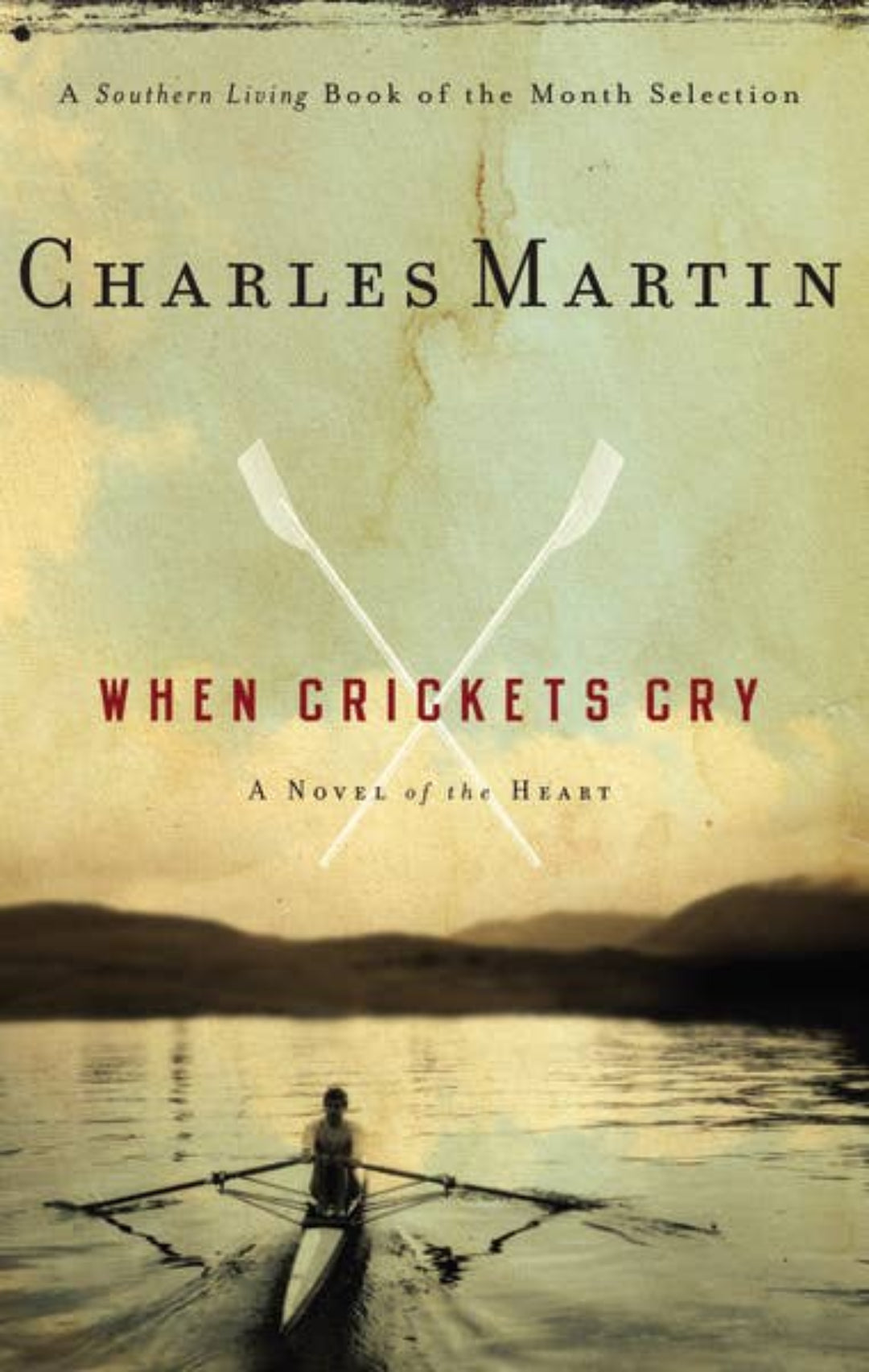Book cover for 'When Crickets Cry' by Charles Martin, featuring a sepia-toned lake scene with a rower in a longboat and crossed paddles above the title.