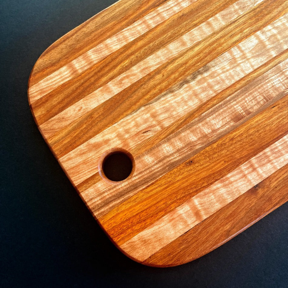The Handcrafted Charcuterie Board or Bread Board is crafted from Tiger Maple and Canary Wood, measuring 18 x 8 x 1. This combination of woods offers remarkable depth. It is then seasoned with Milie's Tung Oil.
