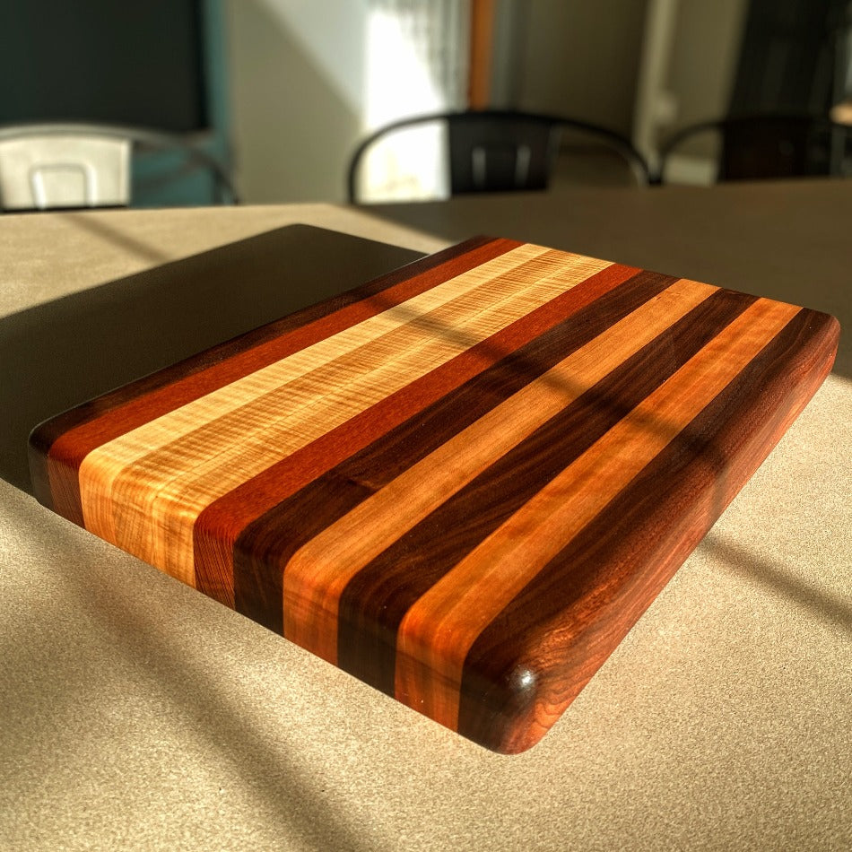 Create a refined atmosphere at every gathering with this exquisite piece. Edge Grain Serving Board is 17 3/4" L, 12" W and 1 3/4" T. It's crafted with Leopard Wood, Padauk, Tiger Maple and Walnut.