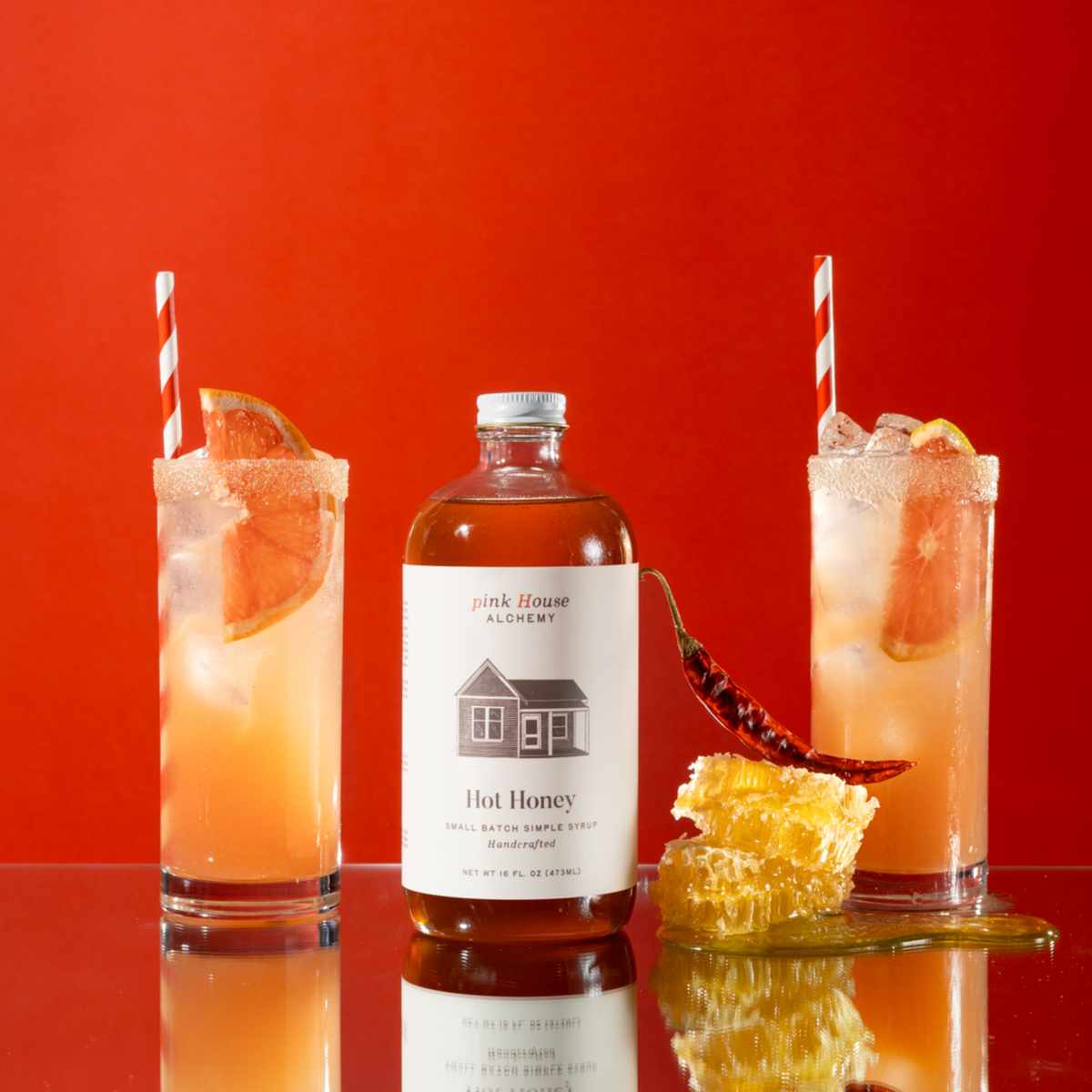 Hot Honey bottle with two cocktails on a red background