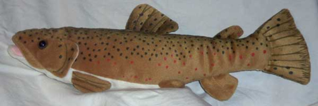 A plush toy fish, resembling a brown trout, made of tan fabric with black spots and red accents, lying on a white fabric background.