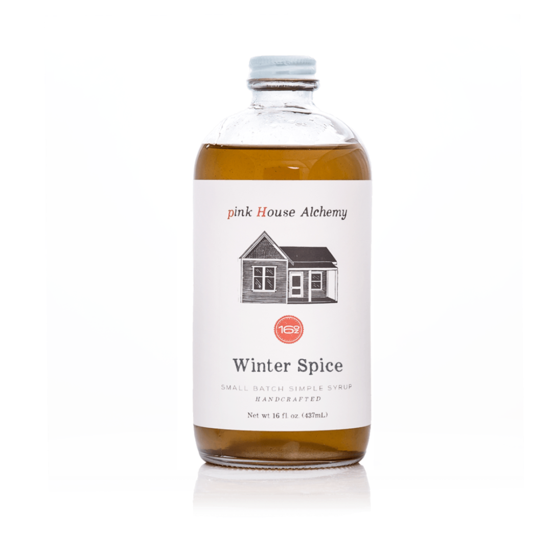 Bottle of 'Winter Spice' syrup from pink House Alchemy on a white background